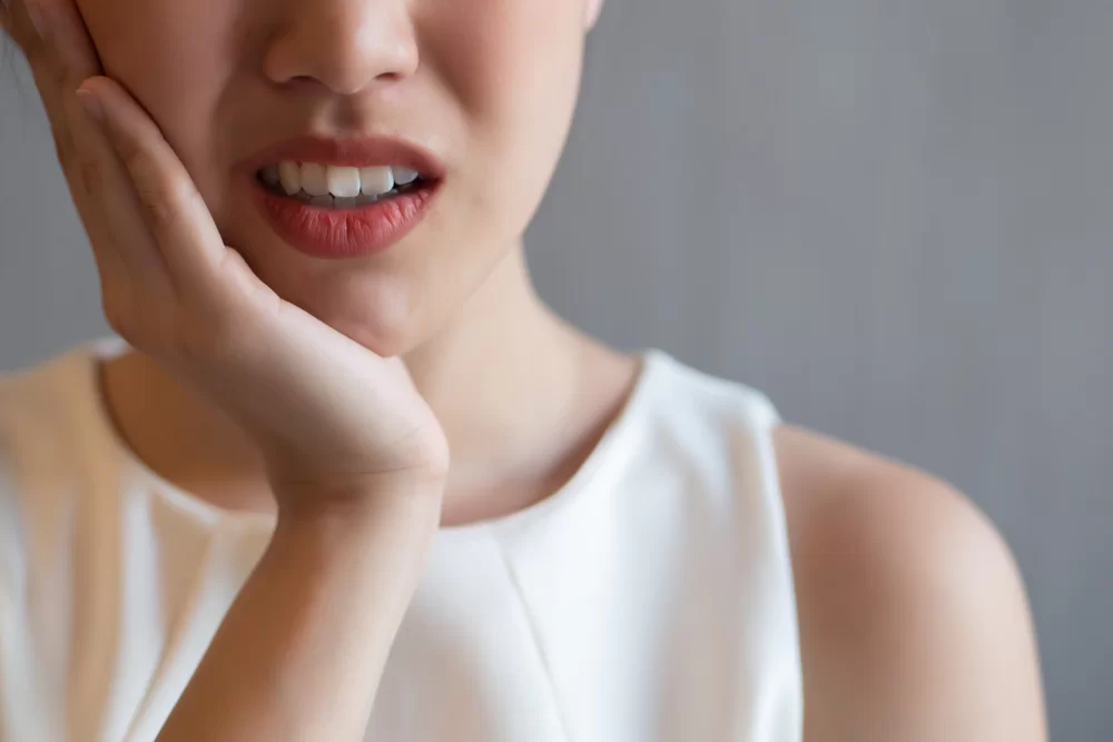 woman holding the side of her jaw due to toothache